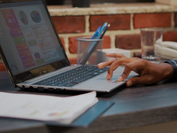Hand typing on digital laptop to work on sales statistics, planning financial development with data report. Business man using computer to create e commerce innovation. Close up